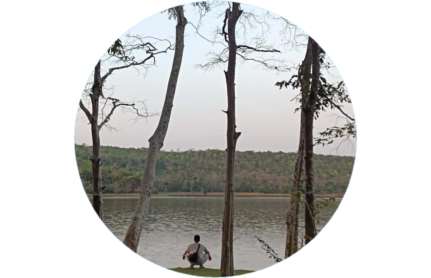 Isyah, crouched by a lake among bare trees